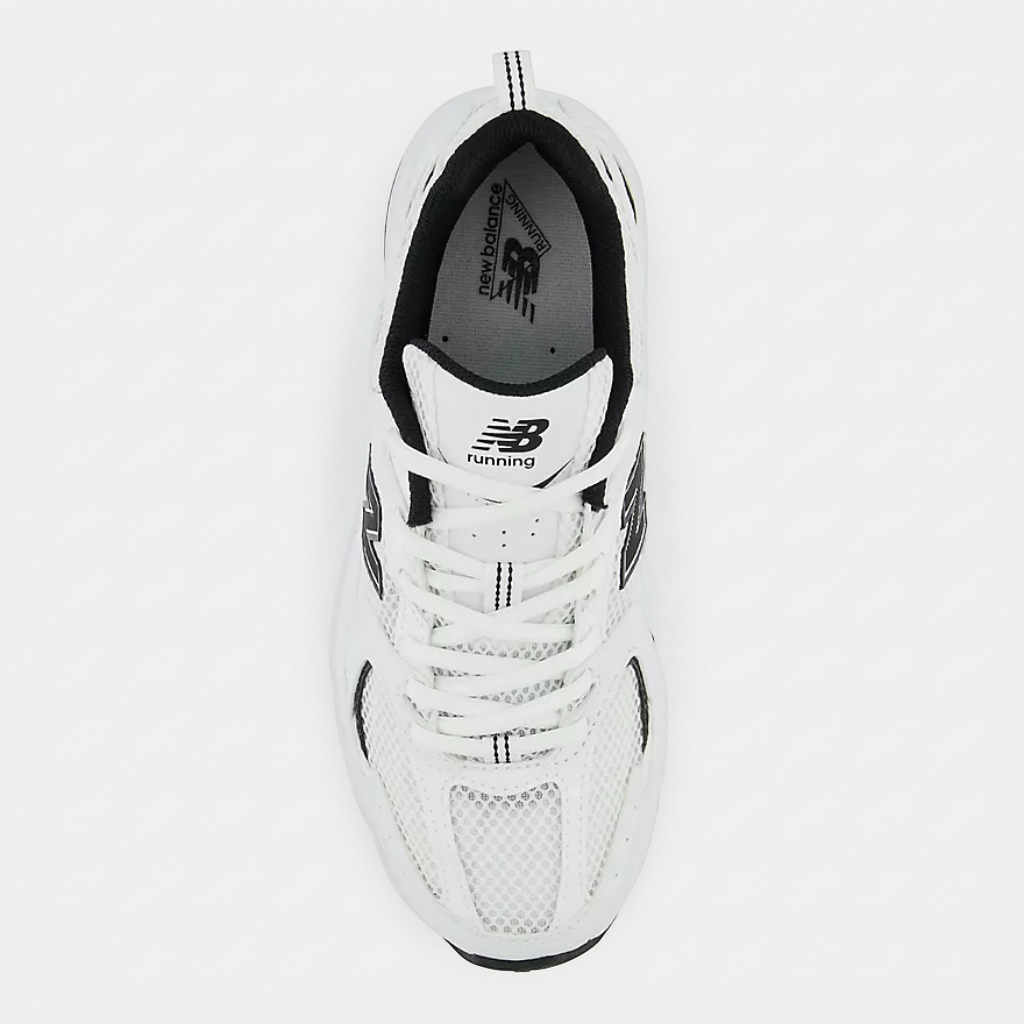 New Balance 530 White Black vista superior Vista lateral das New Balance 530 White Black, destacando a silhueta clássica e o contraste entre o branco e os detalhes pretos.
